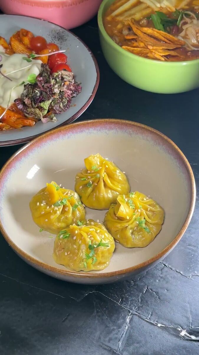 Vegetarian dumplings served with sauce and garnish at EMC Kitchen in Vesu, Surat